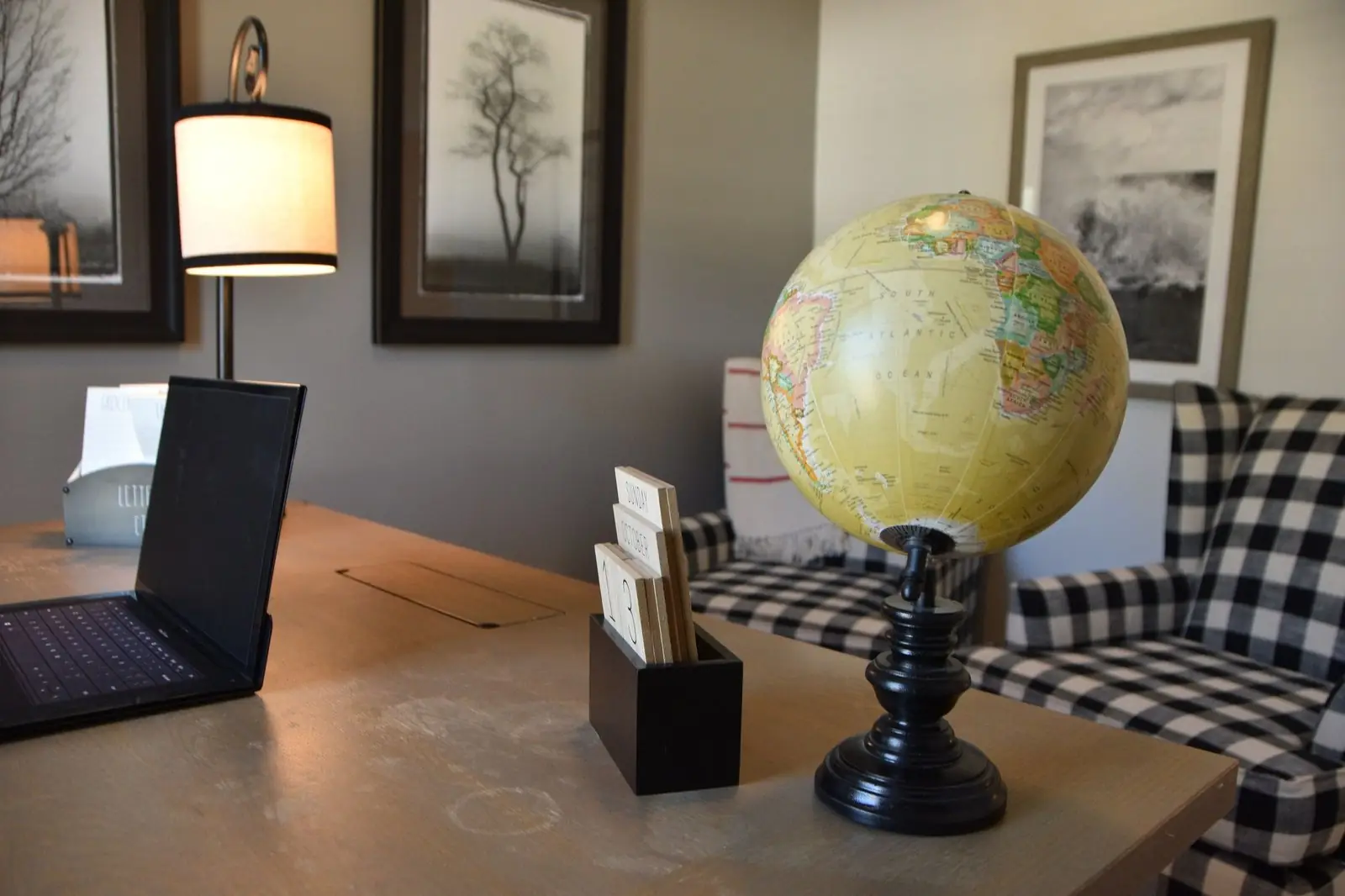 A tidy office desk with a laptop, a globe and a lamp