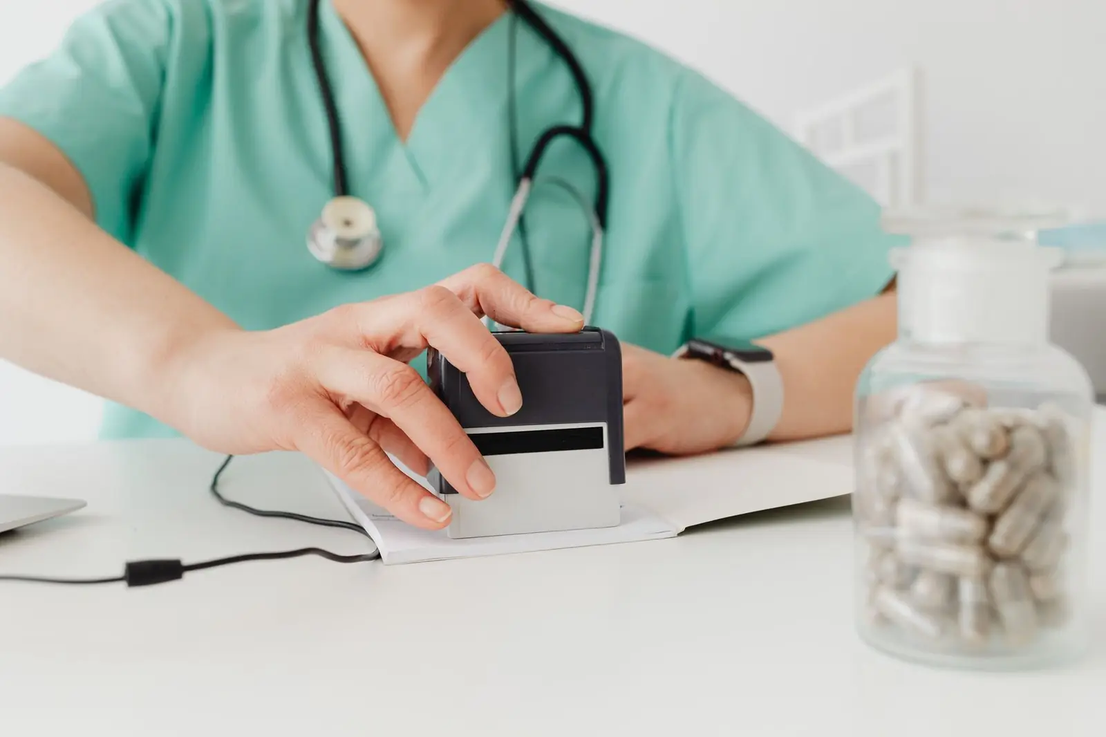 Doctor pressing a stamp onto a paper at a clinic desk, as on a medical certificate
