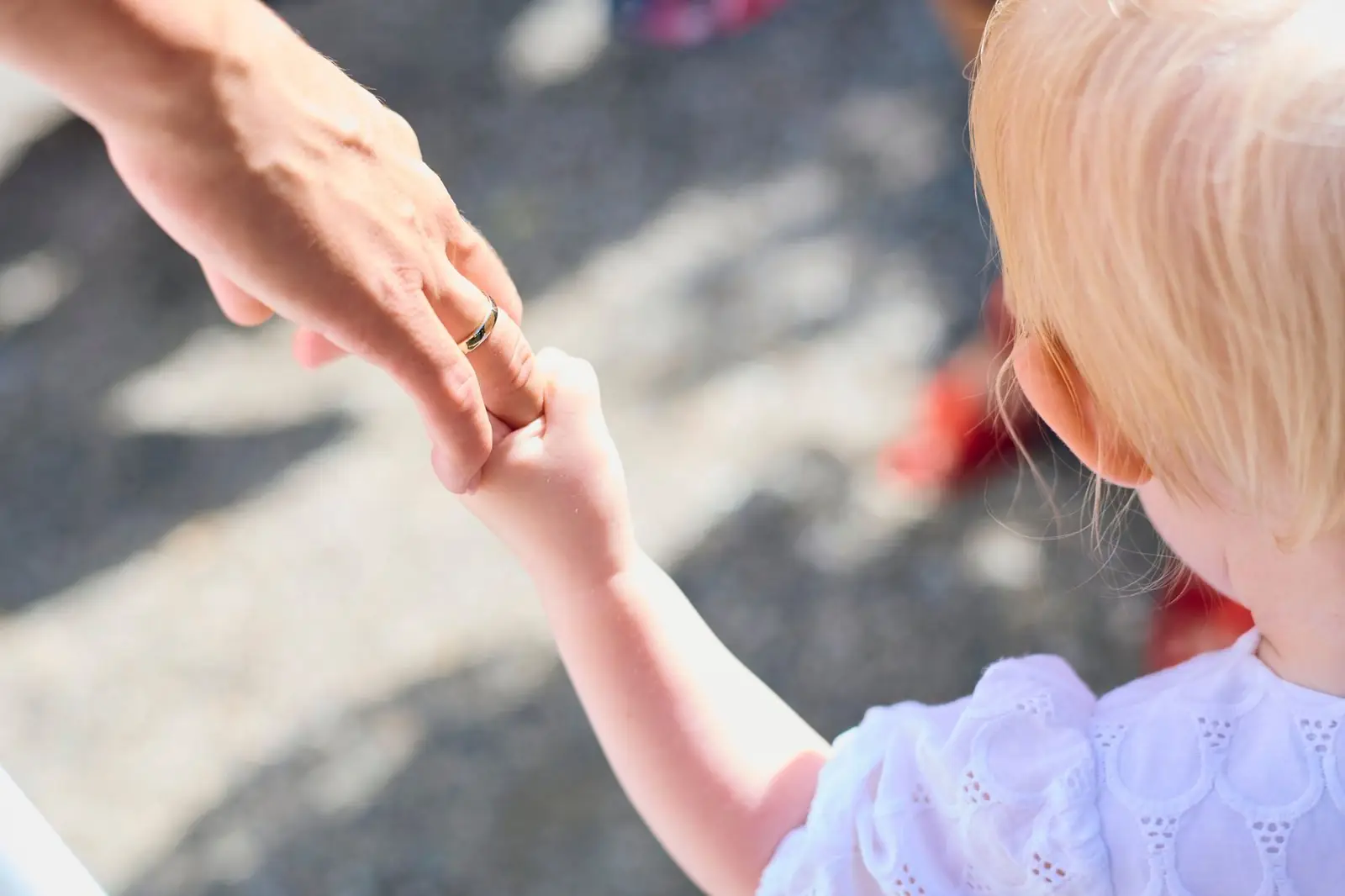 An adult holding a young child's hand while walking
