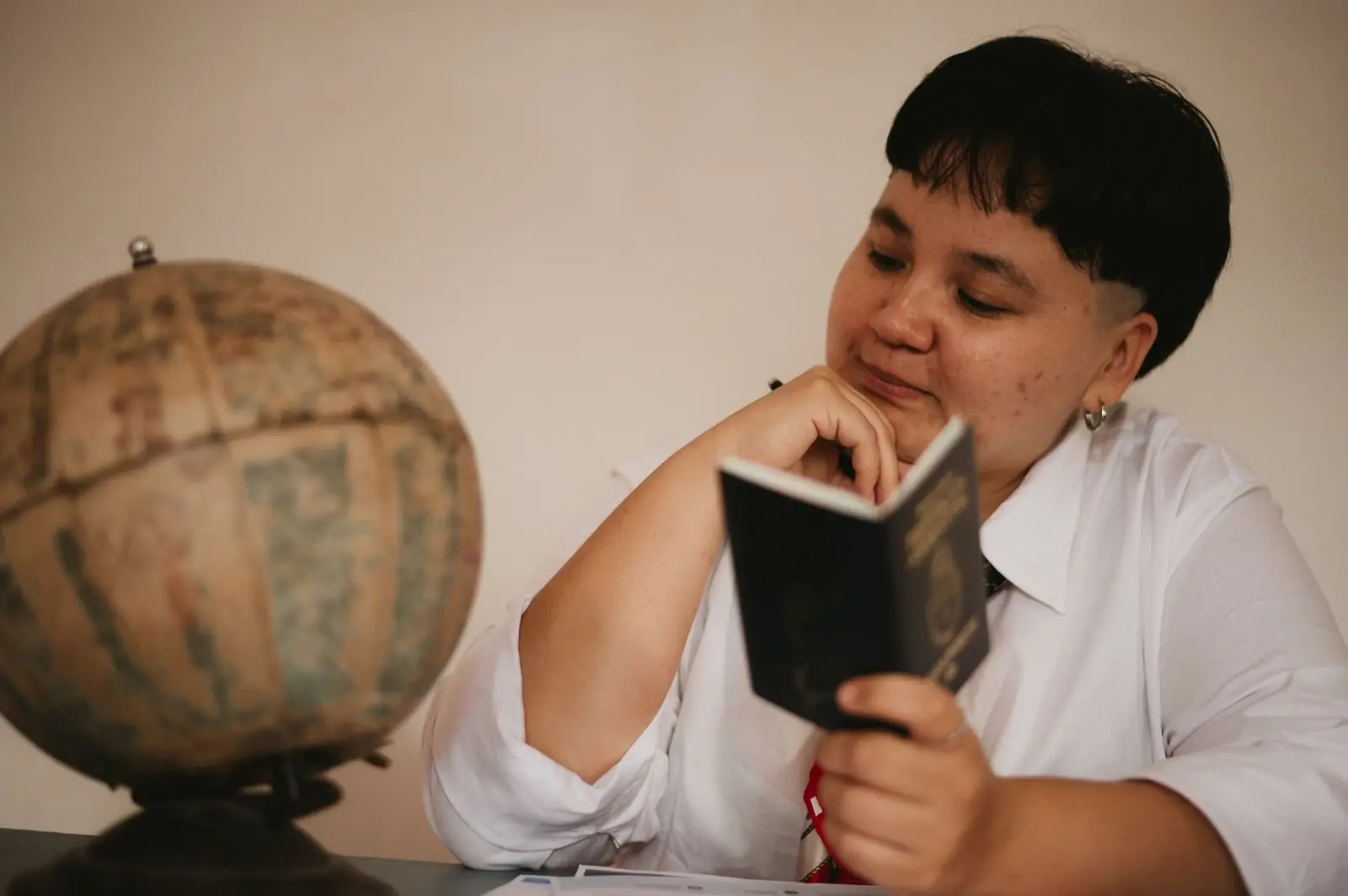 Woman reading a passport beside an old globe