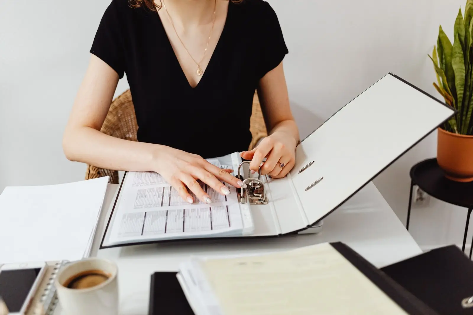 A woman working through a binder of company papers at her desk