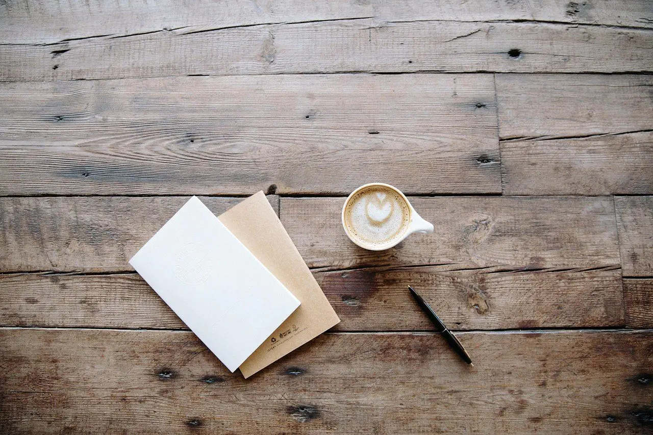 Envelope, pen and coffee cup on a wooden table