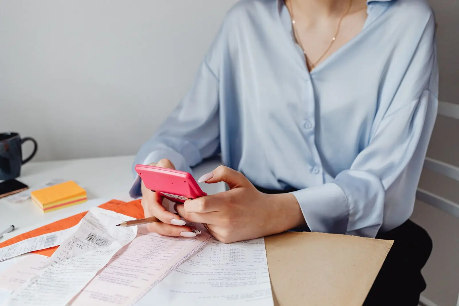 Woman working out costs with a calculator over receipts
