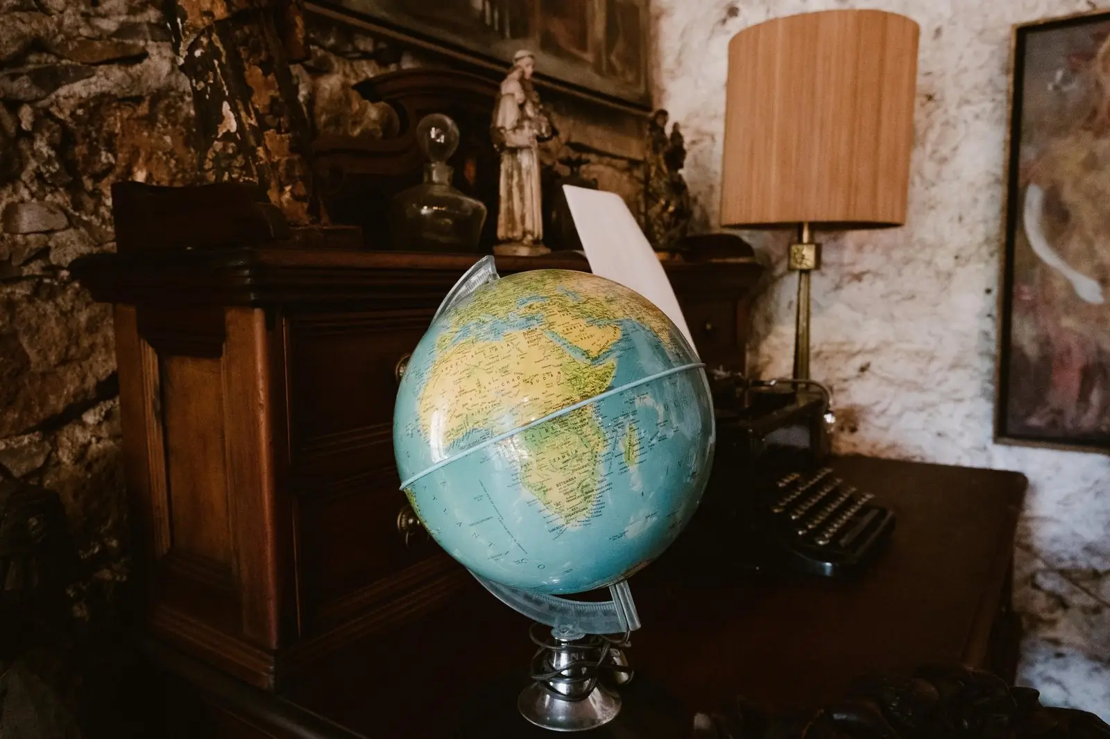 Desk globe in a study beside a wooden cabinet and lamp