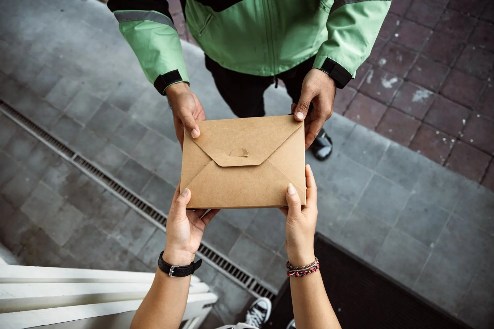 One person handing a brown document envelope to another