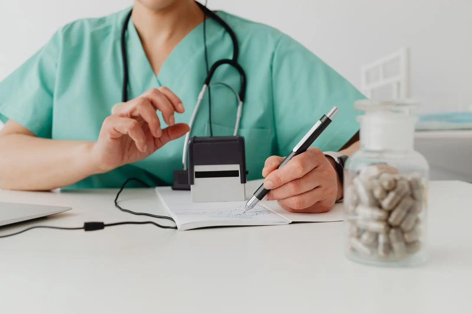Hand signing a paper next to a self-inking stamp on a desk