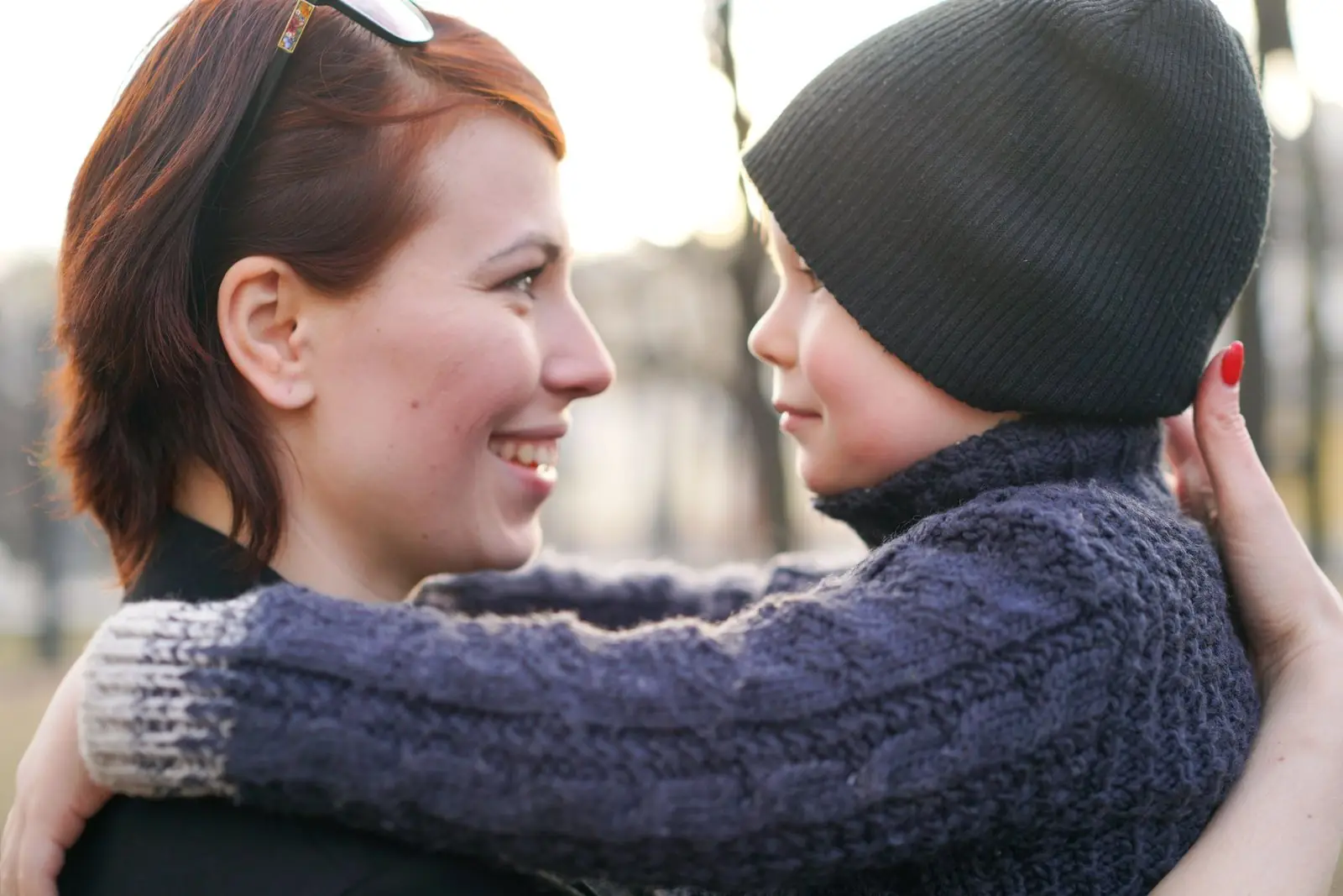 A mother hugging her young son outdoors