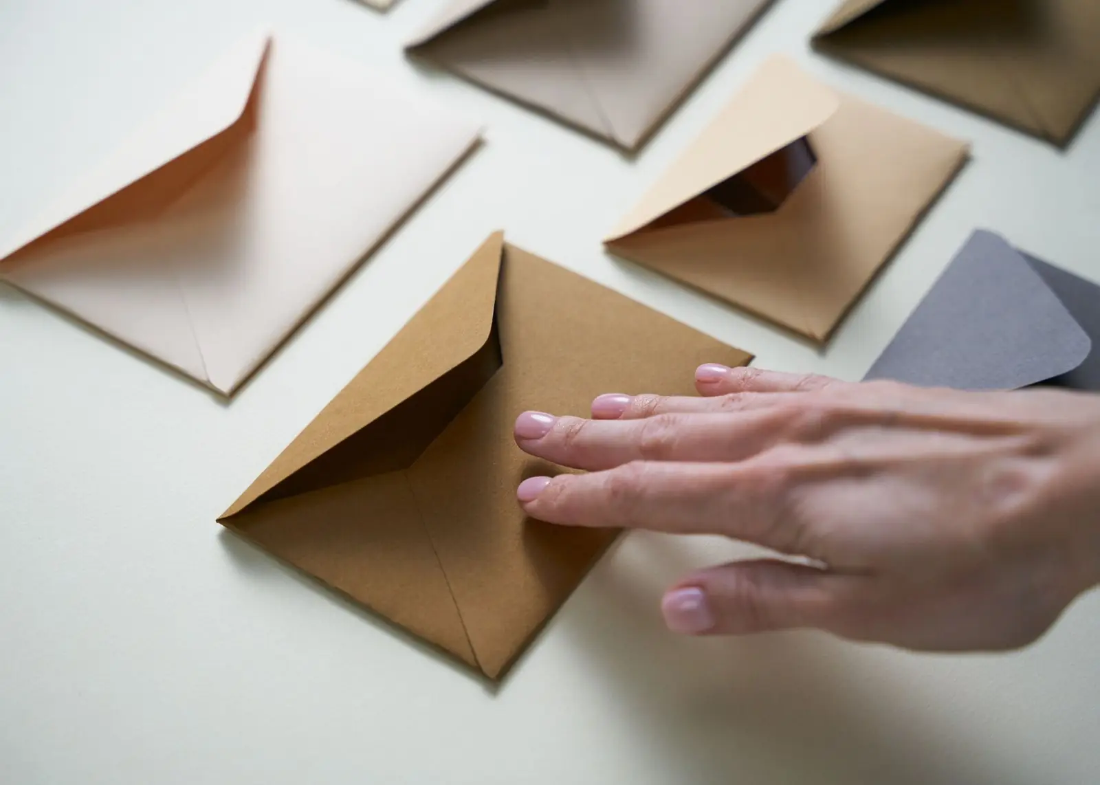 A hand closing one of several brown paper envelopes